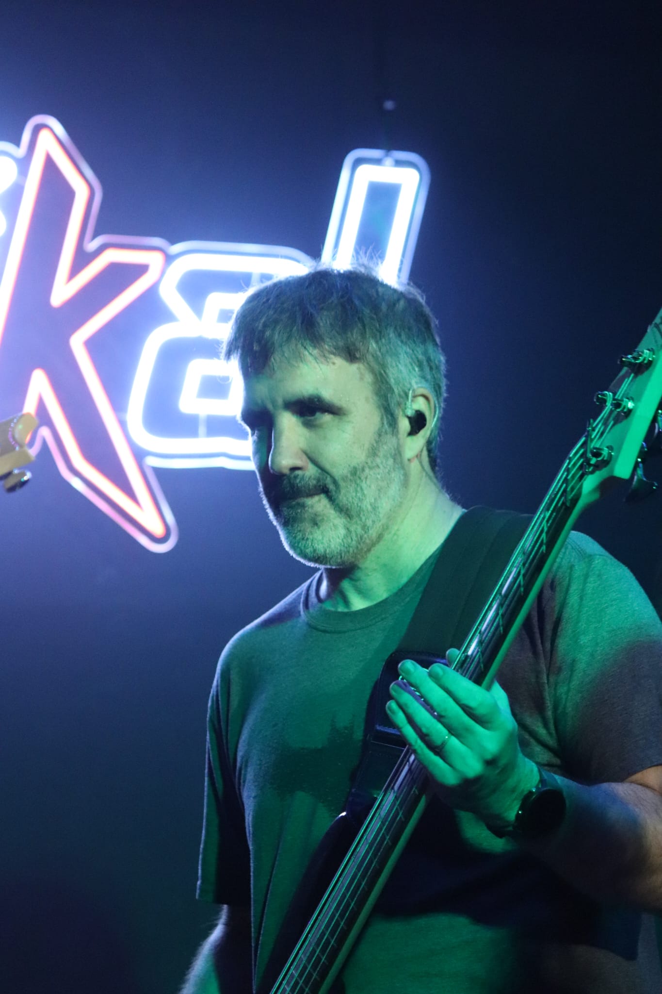 En Bruno tocant el baix sota llum verda davant del rètol de neó
