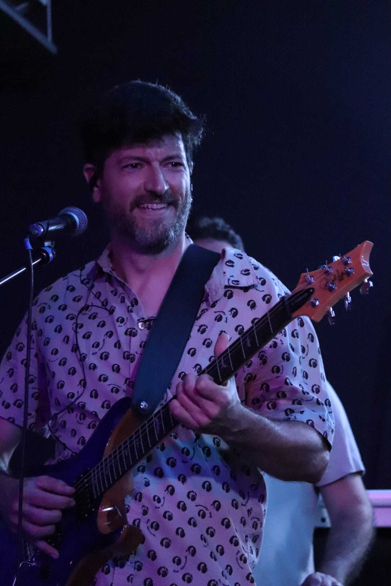 En Lluís somrient al micro amb la guitarra blava